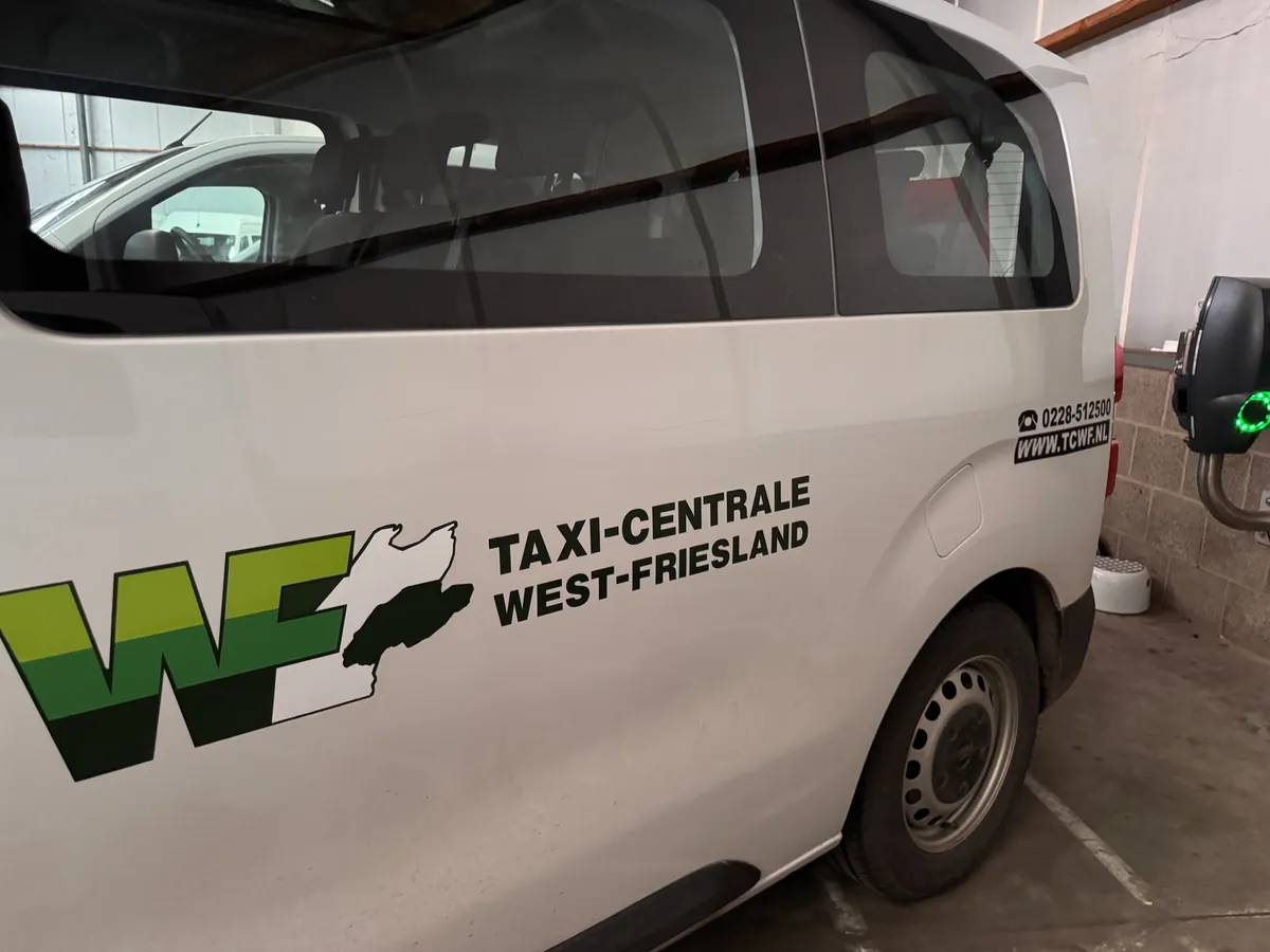Witte taxibus met logo van Taxi-Centrale West-Friesland