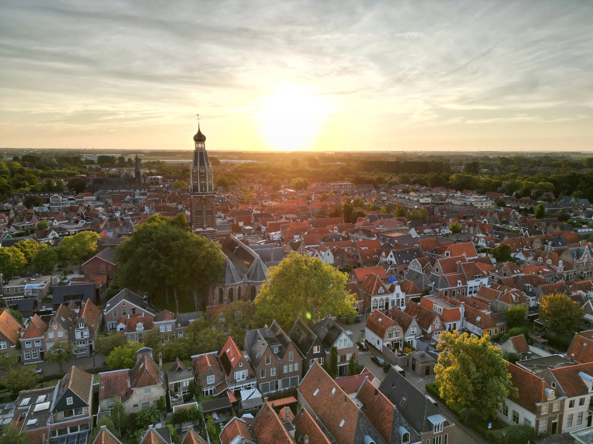 Luchtfoto van Enkhuizen bij zonsondergang, met de kerktoren boven de rode daken